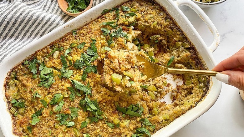 Spooning cornbread dressing from baking dish