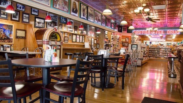 Interior of soda fountain with neon lights, jukebox, and tables