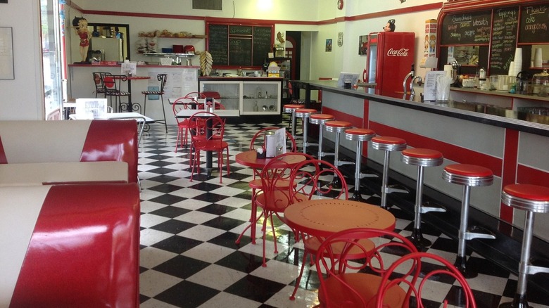 Interior of soda fountain with red stools, tables, and booths