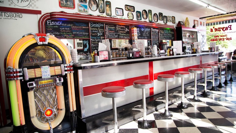 Retro serving counter with jukebox and red stools.
