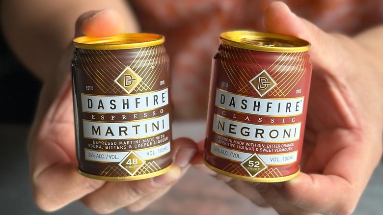 A person holding Dashfire Martini and Negroni cans.