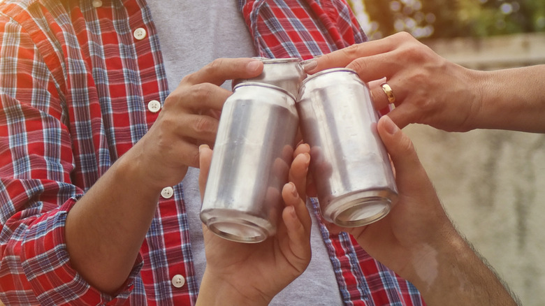 Group celebrating holding canned beverages.