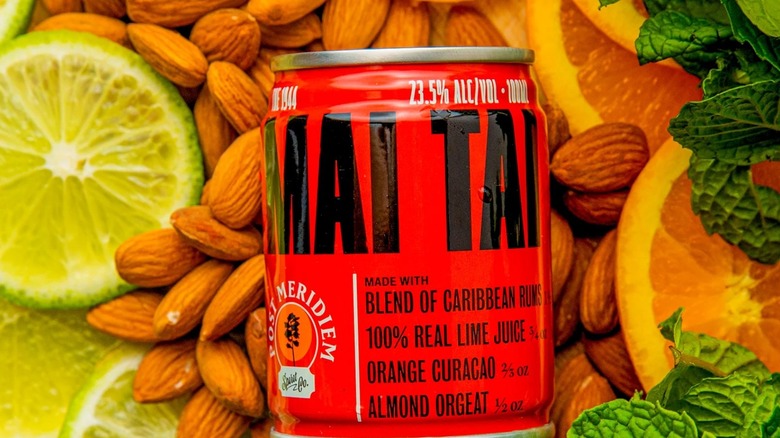 A can of Post Meridiem Mai Tai rests on top of scattered almonds, citrus wheels, and mint leaves.