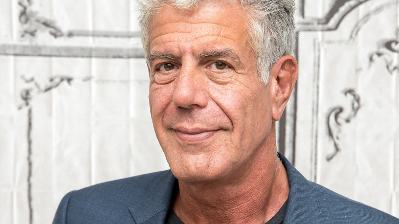 Anthony Bourdain in front of rustic white background.