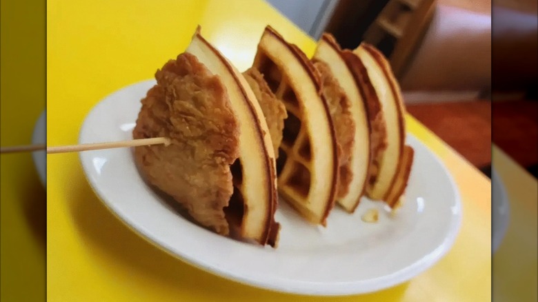 Chicken and waffles on skewer on yellow counter.