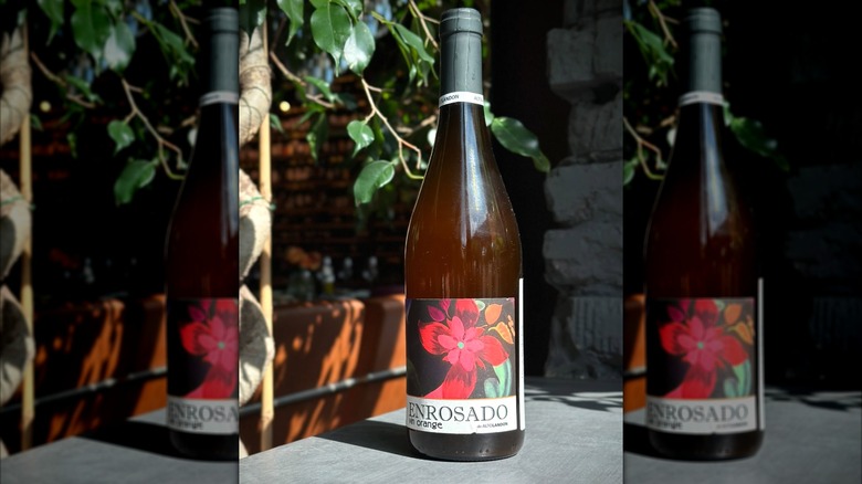 two hands with wine glasses, wine bottle, and flowers