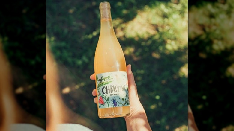 hand holding bottle of wine in sun