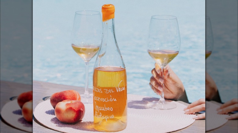 bottle of wine with two glasses by poolside