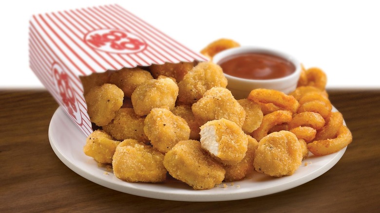 popcorn chicken bites spilling out of a popcorn bag onto a plate