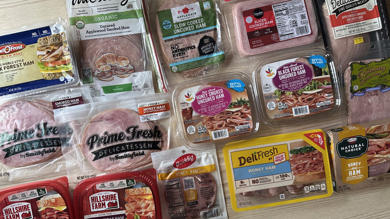 Packages of sliced deli ham arranged on wooden table