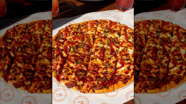 A thin crust pizza from Nancy's Pizzeria resting a piece of branded deli paper.