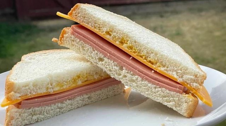 A bologna and cheese sandwich on White Bread sitting on a plate