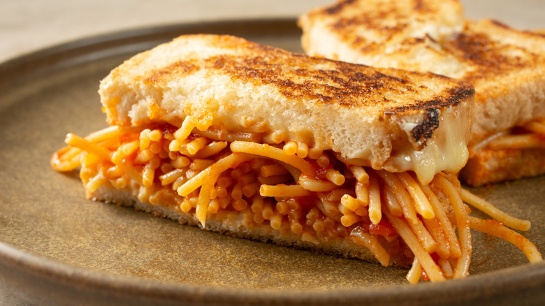 A spaghetti sandwich on toasted bread sitting on a plate