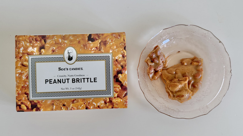 Box of Peanut Brittle next to candy on a plate