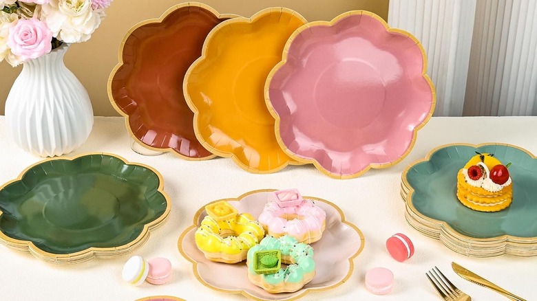 Zuqmzuq Boho Color Paper Plates are staged on a table, some standing upright, others with pastries