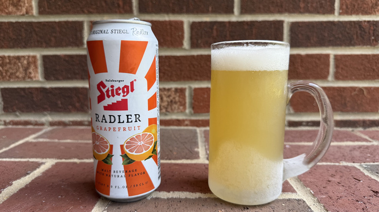 Glass of pale yellow radler next to Stiegl grapefruit radler can