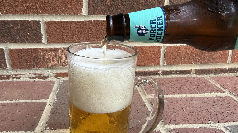 Topping off a beer glass with bottle of Samuel Adams Porch Rocker