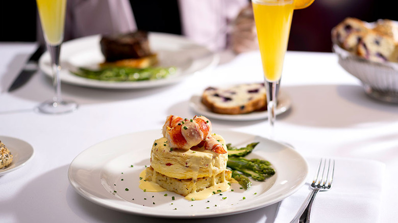 A white plate featuring a lobster fritatta and asparagus, blueberry bread, mimosas, and filet mignon