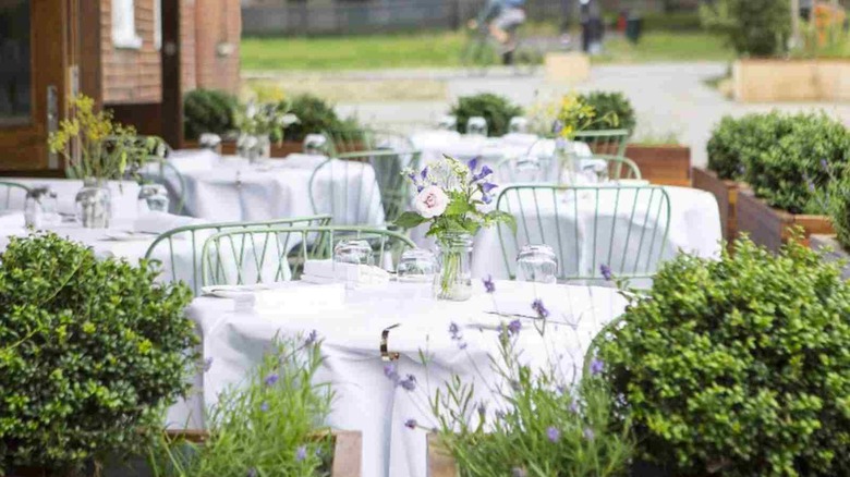 Outdoor seating at Trinity with white tablecloths, green chairs, and plants