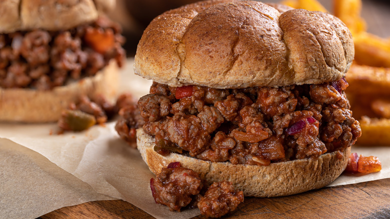 Overflowing sloppy Joe on wheat roll with fries in background
