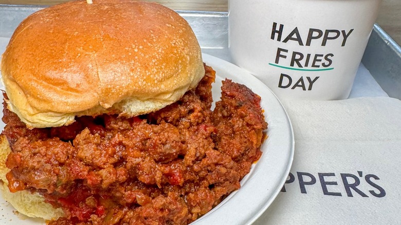 Overflowing sloppy Joe on paper plate with fry container and napkins at Schnipper's in New York City
