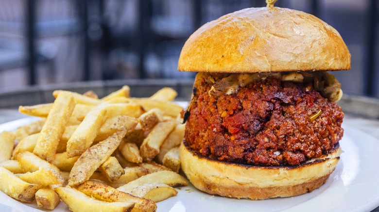Firm meatloaf-like sloppy Joe on bun with fries on plate at School House Kitchen & Libations