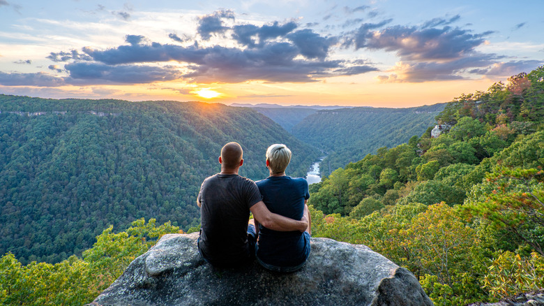 Two people sitting on a rock, looking out over New River Gorge