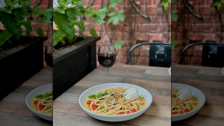 Bowl of pasta and a glass of wine on a table outside