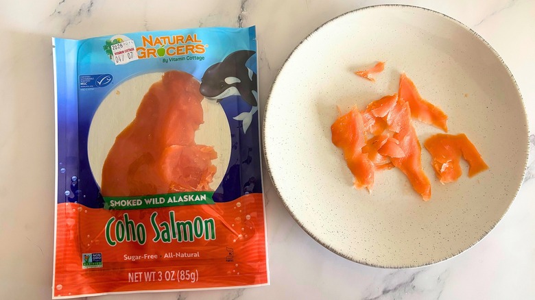 Natural Grocers smoked salmon on white plate next to packaging on white marble surface