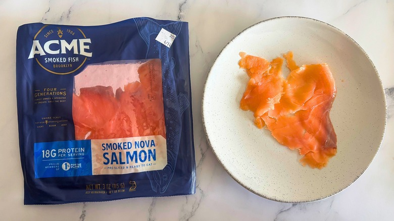 Acme smoked salmon on white plate next to packaging on white marble surface