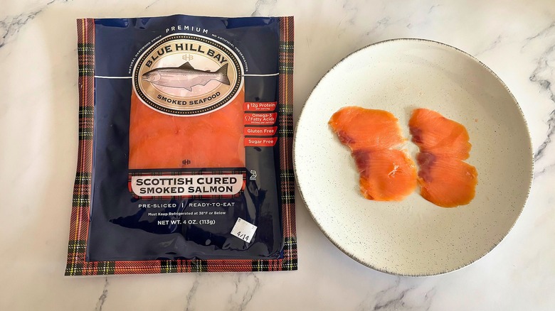 Blue Hill Bay smoked salmon on white plate next to packaging on white marble surface