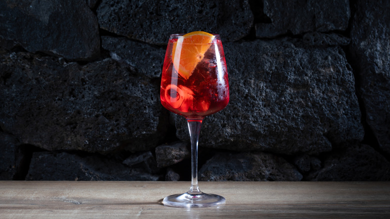 A glass of Campari Spritz with orange slice against a dark background