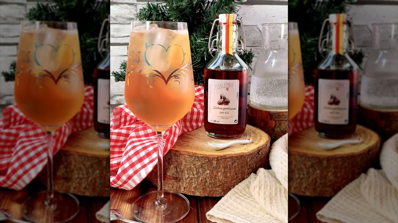 A glass of Zirbenz Spritz with Zirbenz Bottle on wood and a kitchen towel