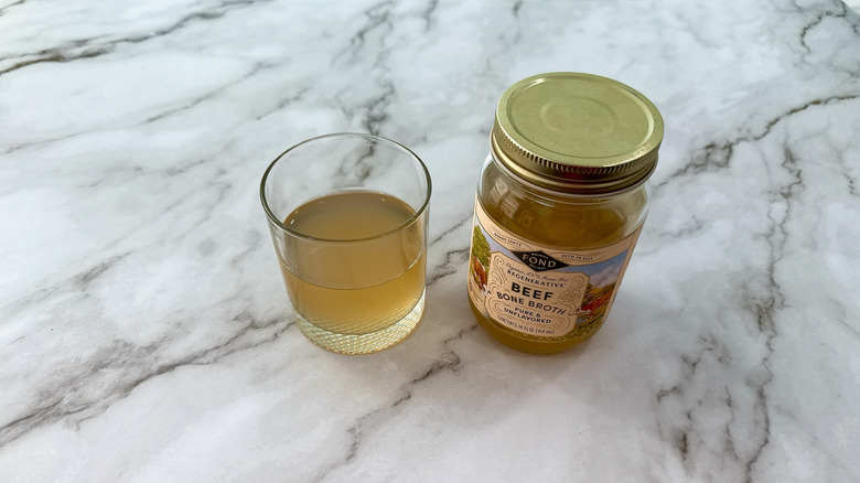 Jar of fond bone broth and glass of broth