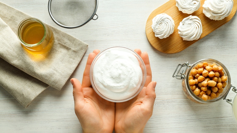 Person holding bowl of cream with chickpeas and aquafaba