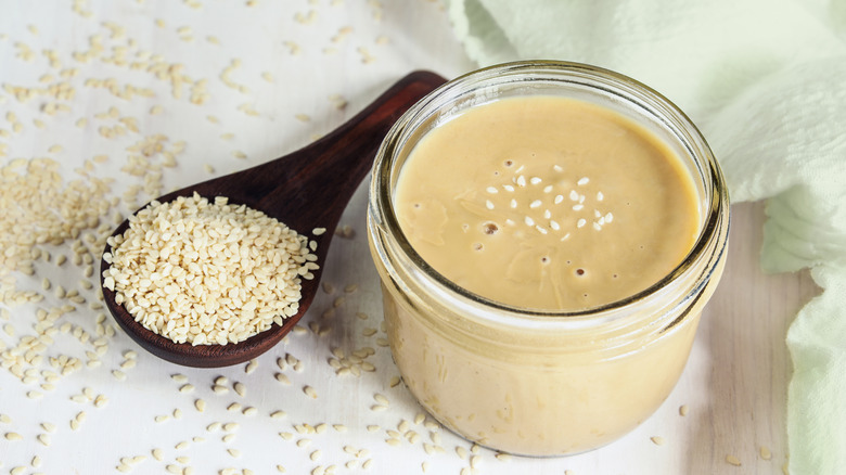 Jar of tahini next to sesame seeds