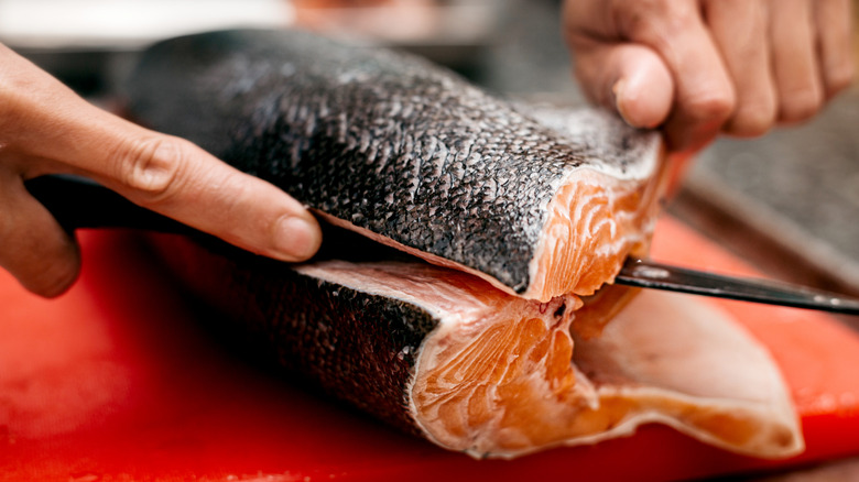 A person cutting a fish lengthways with a knife