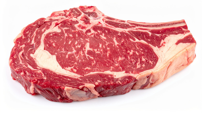 Thick raw ribeye steak on white background