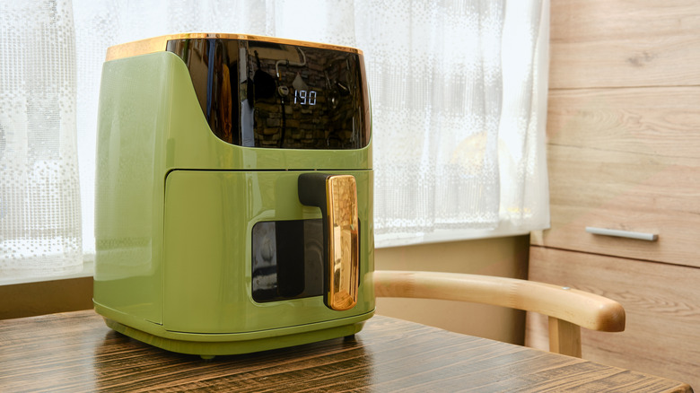 Preheating green air fryer on wooden table