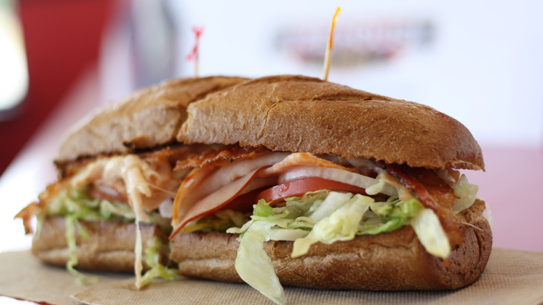 A sliced submarine sandwich filled with lettuce and proteins