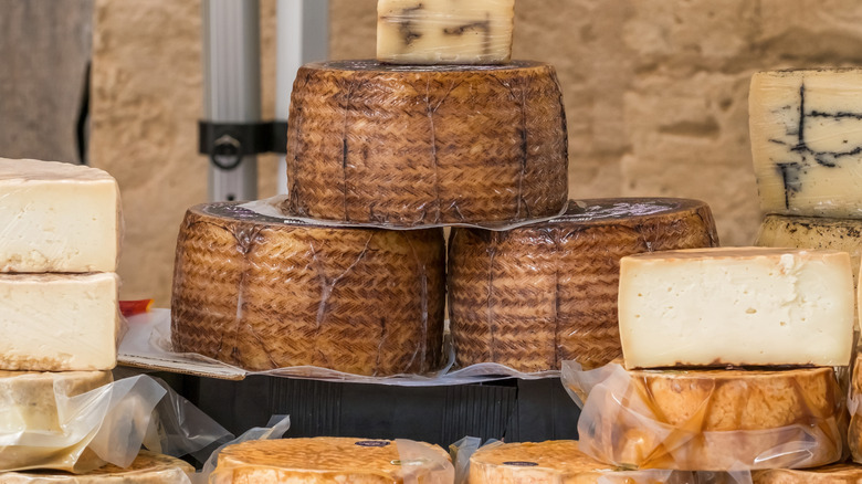 A table stacked with different types of cheese wheels