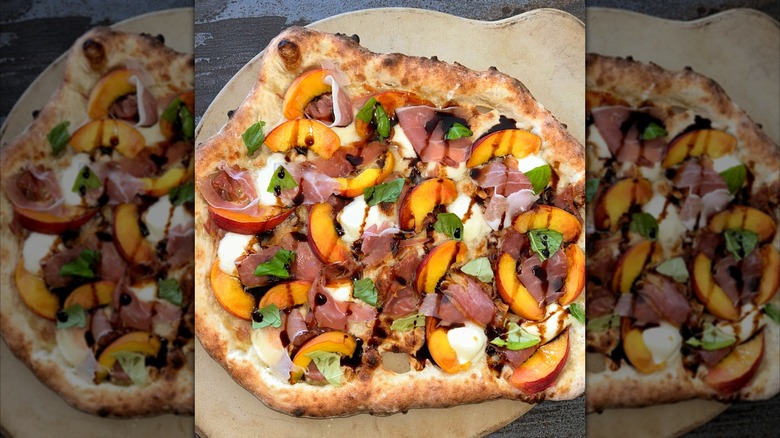 Pizza with burrata, peaches, proscuitto, and balsamic vinegar on wooden board