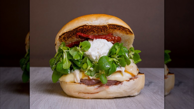 Beef burger with burrata cheese, fresh basil, sundried tomatoes, and aioli
