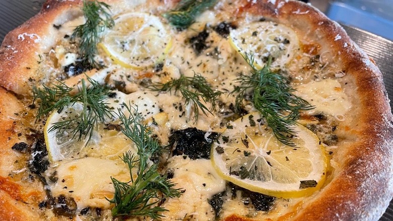 A seafood pizza with dill and lemon slices