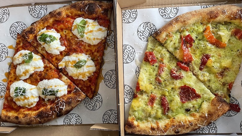 Slices of pizza with burrata and peppers on parchment