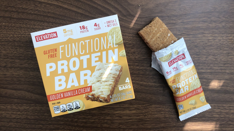 A box of Aldi Elevation golden vanilla cream functional protein bars with an open bar beside it