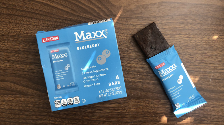 A box of Aldi Elevation Maxx blueberry bars and an open bar beside it on a table