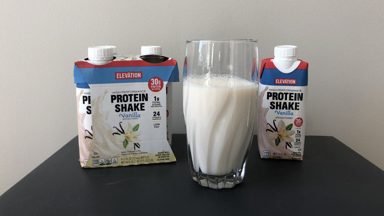 Bottles of Aldi Elevation vanilla protein shake with some poured into a glass