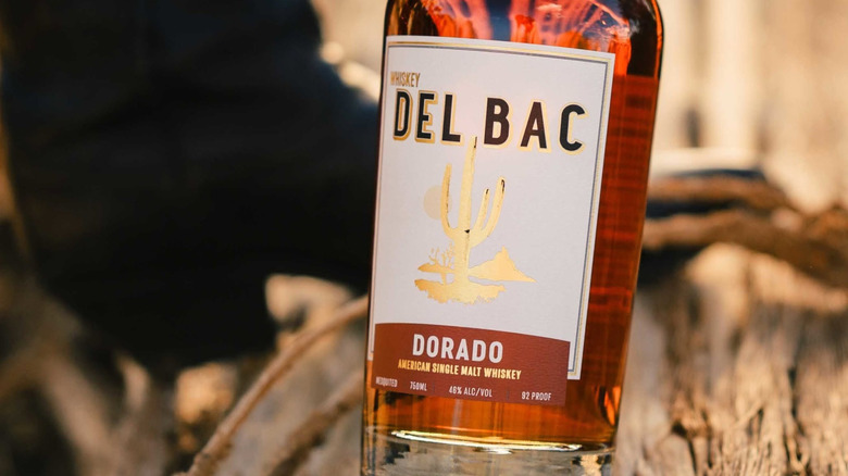 A close shot of a bottle of Del Bac Dorado with a blurred nature background