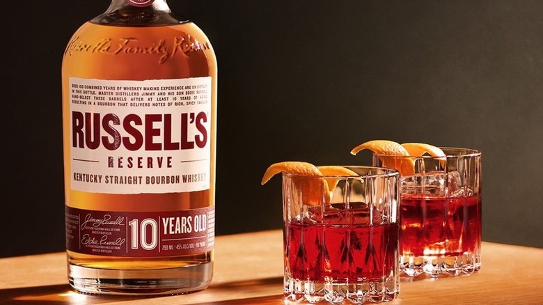 A bottle of Russell's Reserve 10-year on a table next to two identical cocktails
